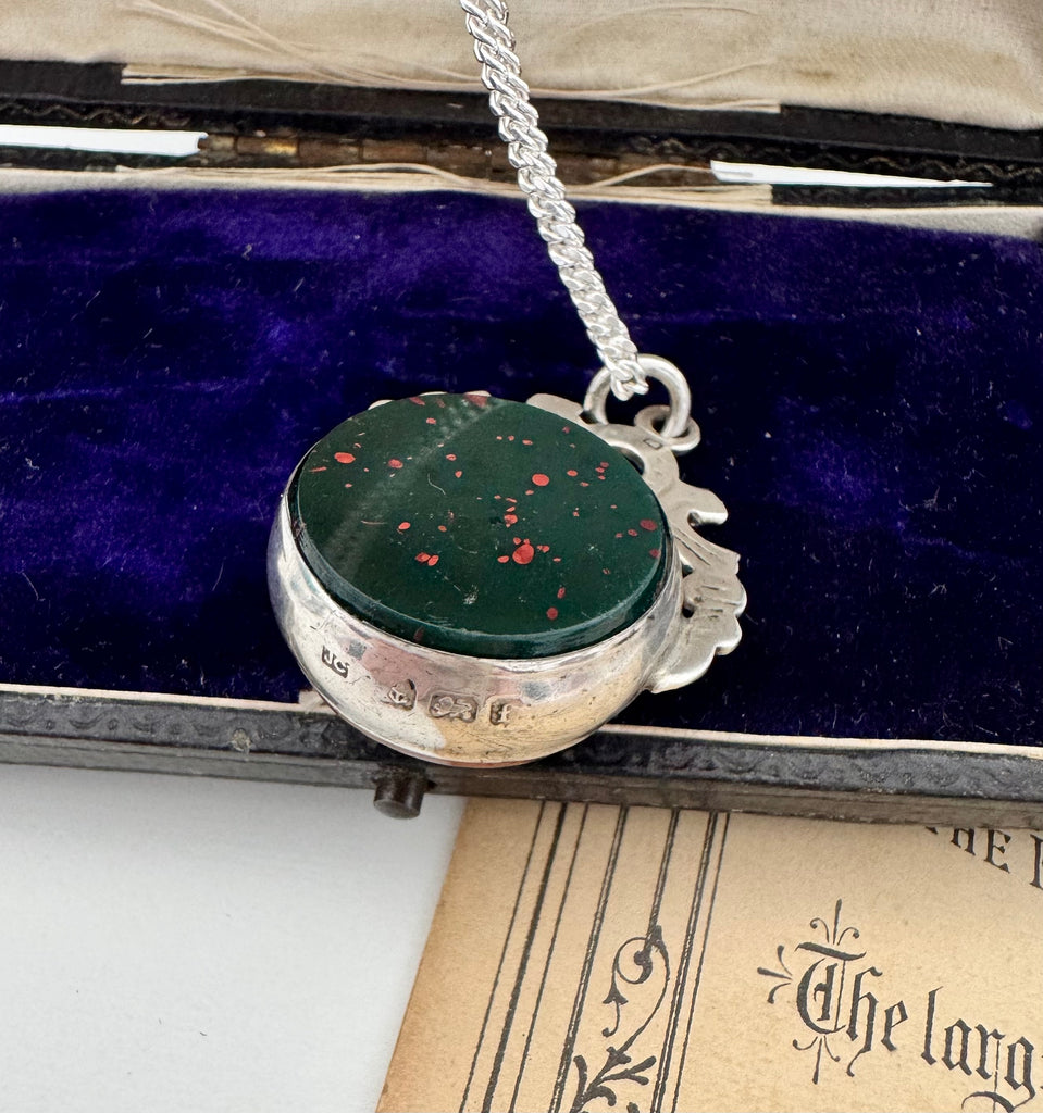 Antique 1905 watch fob necklace with a dark green bloodstone in a silver setting on an open jewellery box