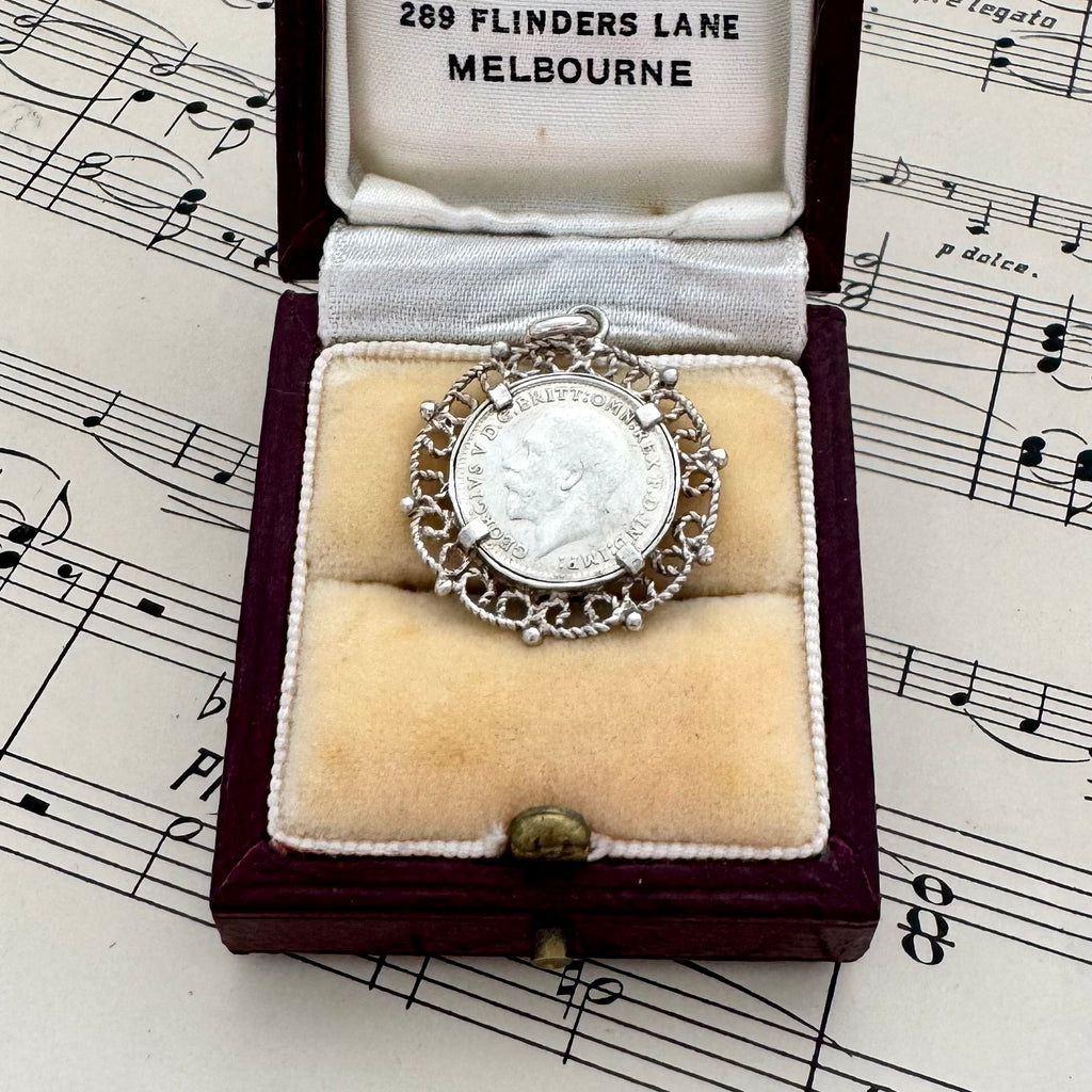 Antique 1918 silver threepence charm or pendant in a box on sheet music