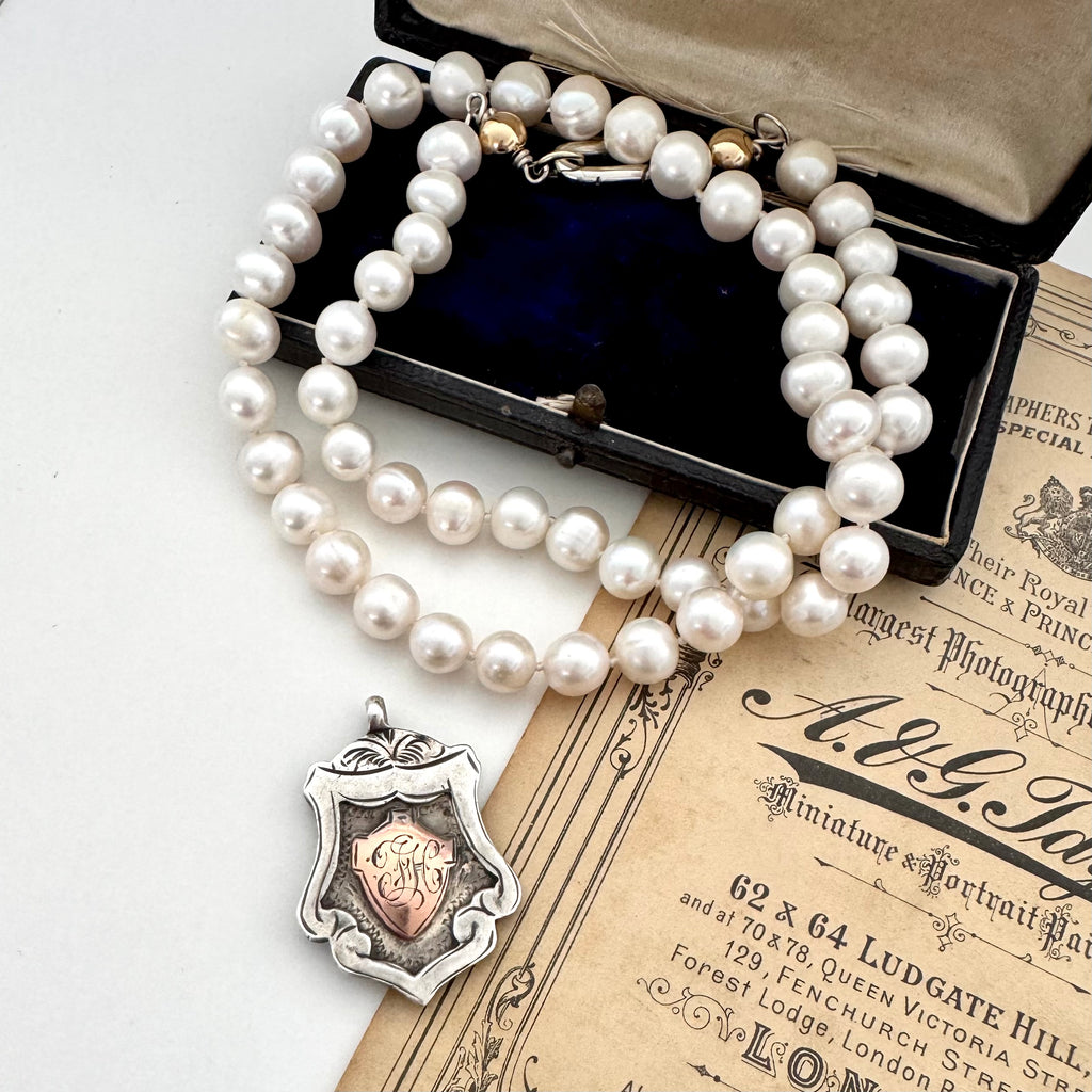 1919 sterling silver watch fob and pearl necklace on a vintage jewellery box and old photo