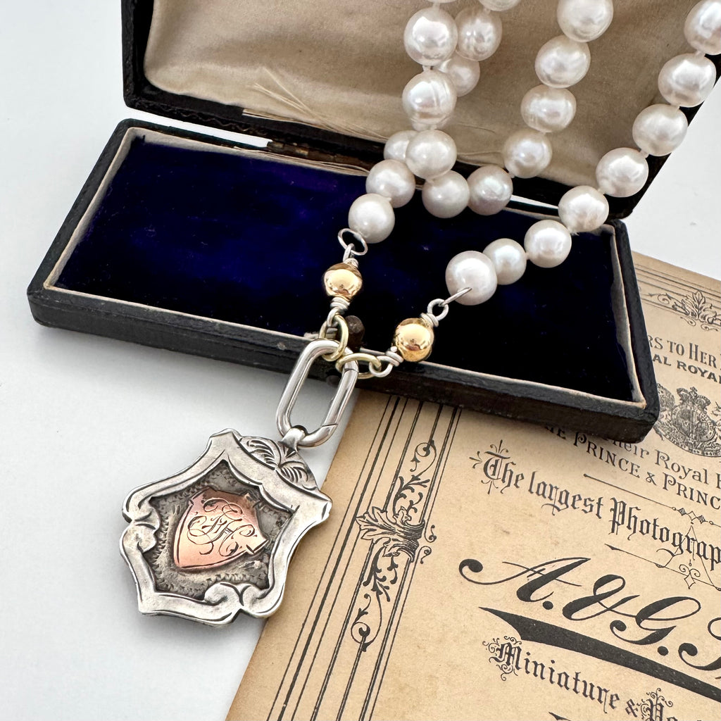1919 sterling silver watch fob and pearl necklace on a vintage jewellery box and old photo