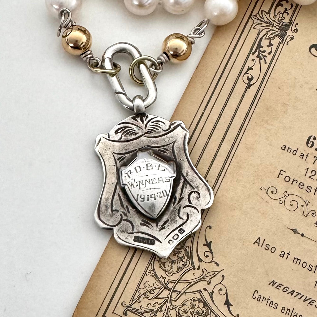 1919 sterling silver watch fob and pearl necklace on a vintage jewellery box and old photo