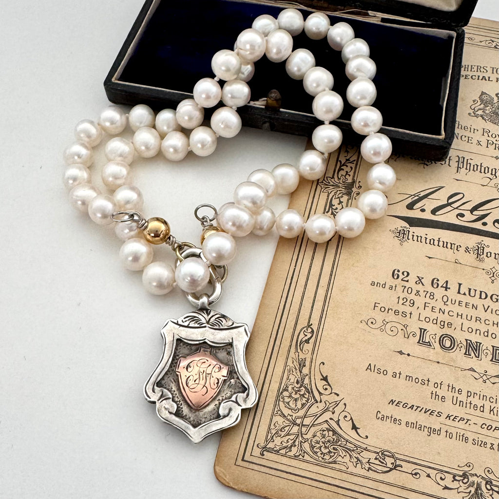 1919 sterling silver watch fob and pearl necklace on a vintage jewellery box and old photo