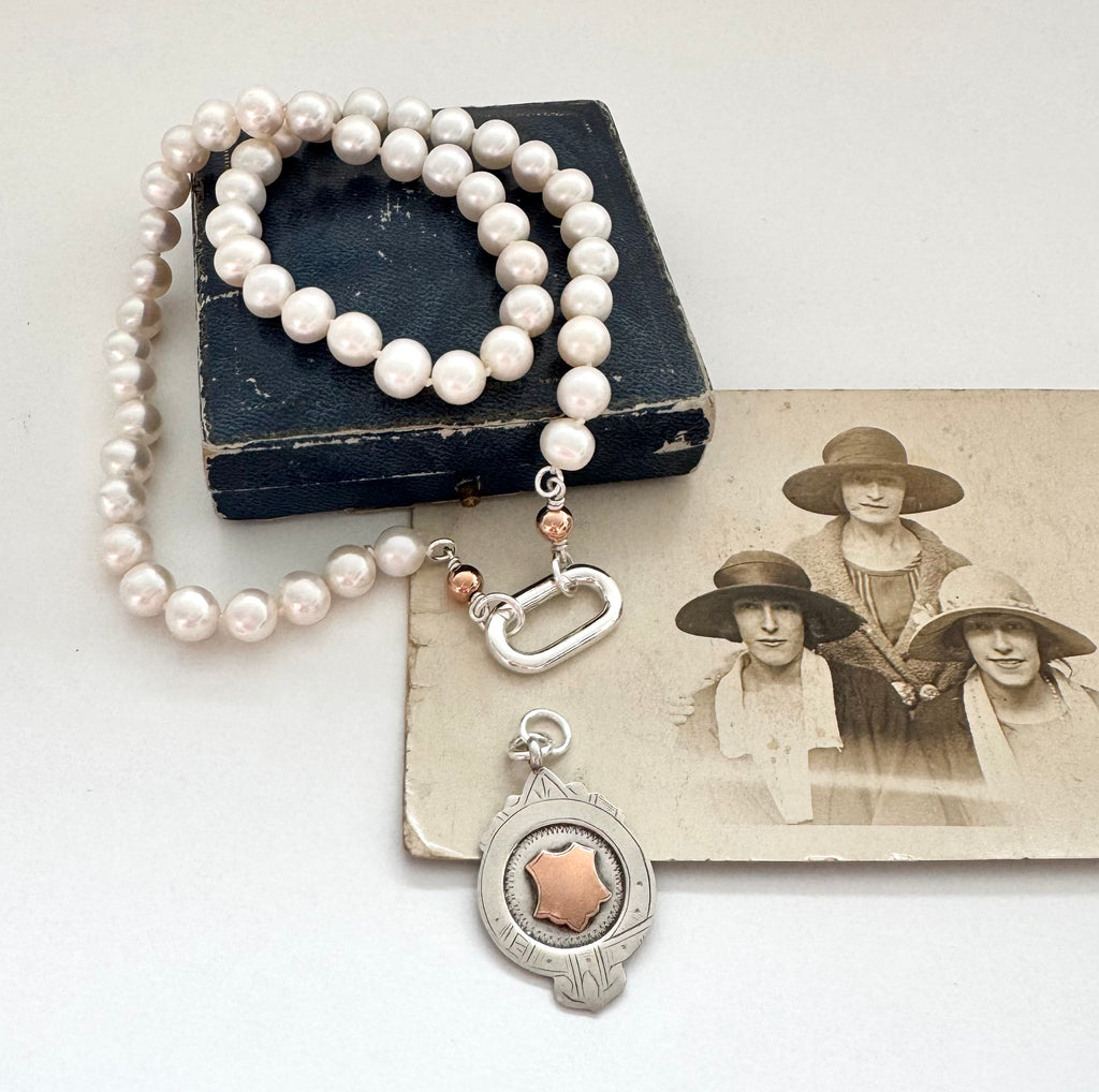 1932 silver and rose gold watch fob pearl necklace on an old jewellery box and photograph of women in the 1920's