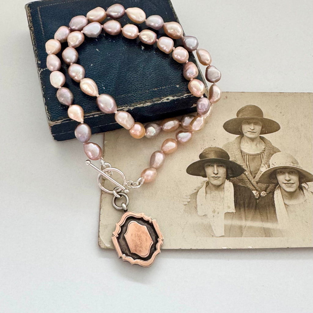 Pearl necklace and 1933 watch fob with a silver clasp on an old photograph of women wearing hats.
