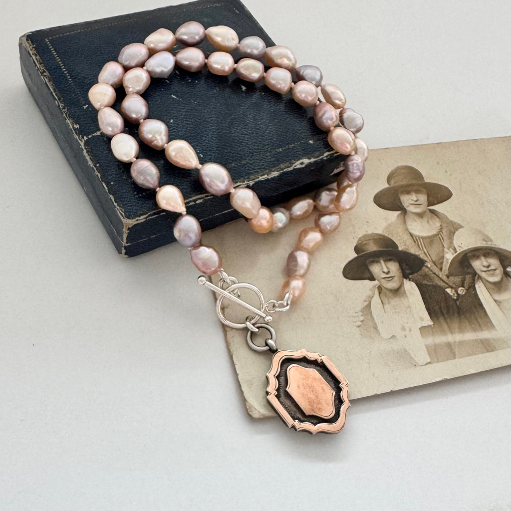 Pearl necklace and 1933 watch fob with a silver clasp on an old photograph of women wearing hats.