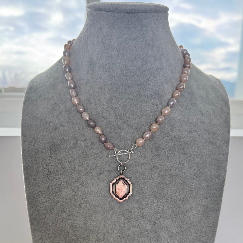 Pearl necklace and 1933 watch fob with a silver clasp on a grey mannequin