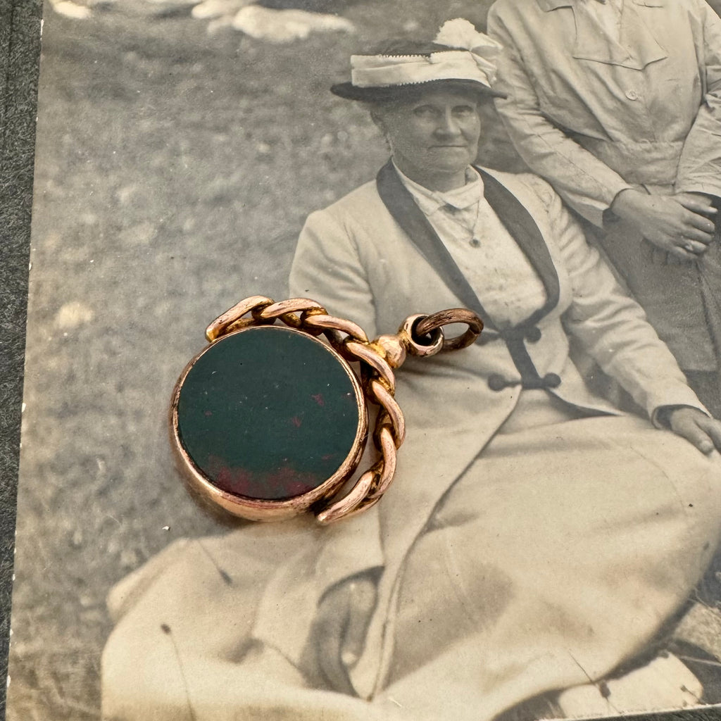 9ct rose gold antique swivel fob with a dark stone on an antique photo of an old woman