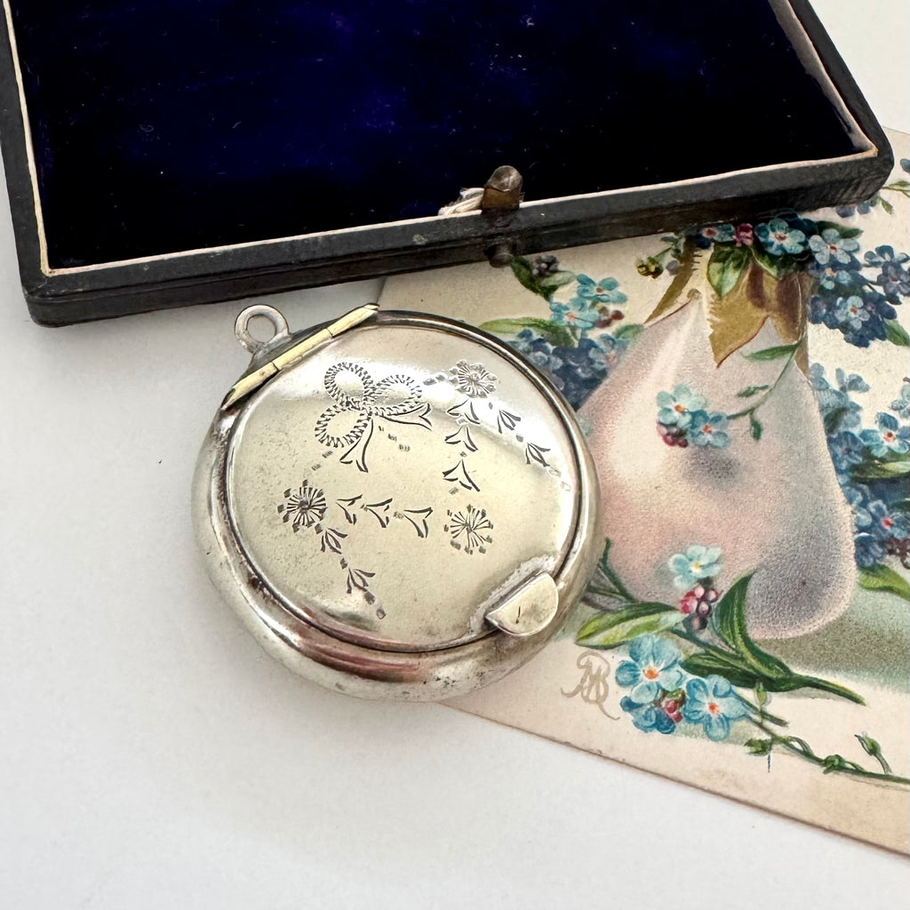 Silver compact mirror with floral design on a floral-themed card
