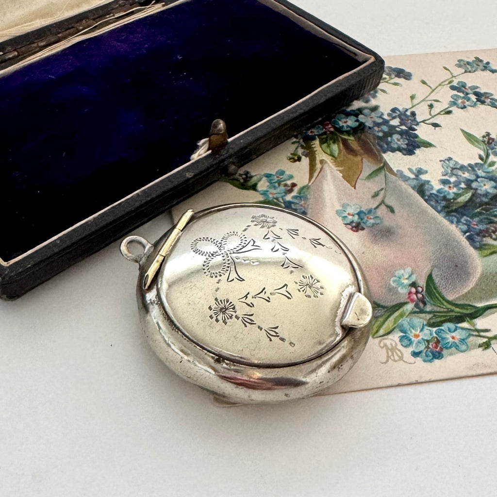 Silver compact mirror with floral design on a floral-patterned card