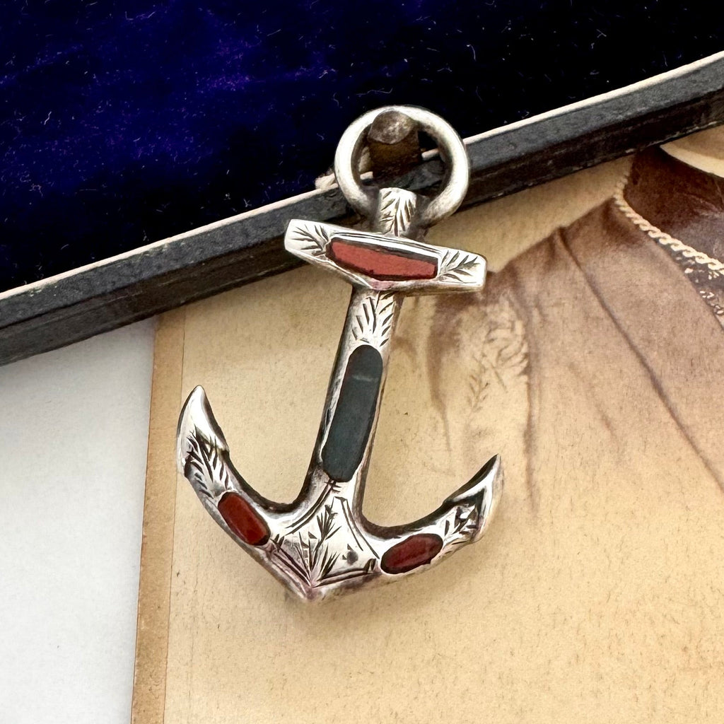 Antique sterling silver and agate anchor brooch on a textured surface