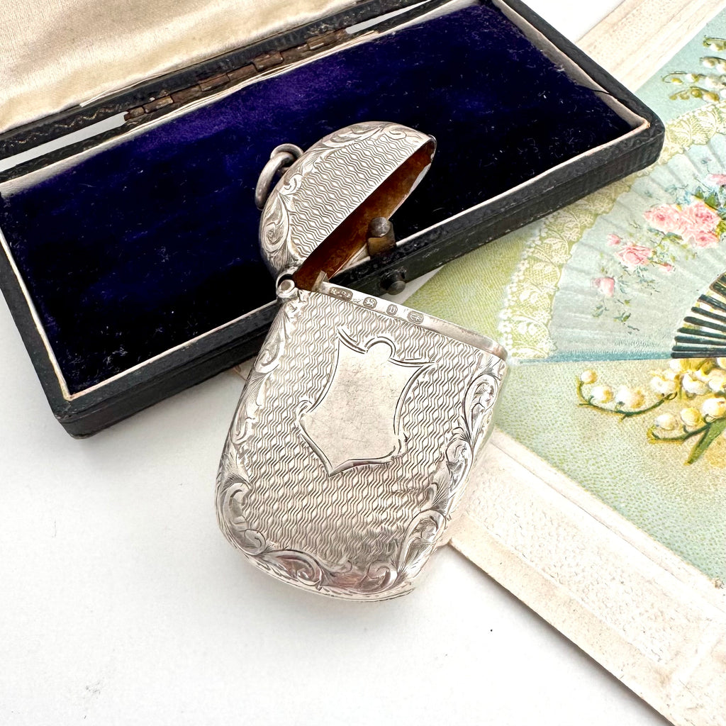 Antique 1879 Victorian silver vesta case on a white background with a vintage postcard and old box in the background.