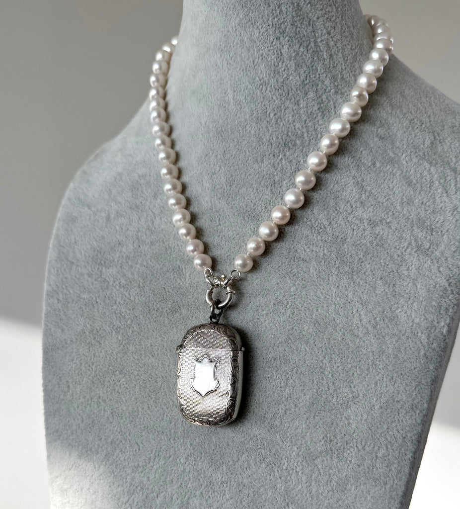 Antique 1879 Victorian silver vesta case on a on a pearl necklace on a grey mannequin