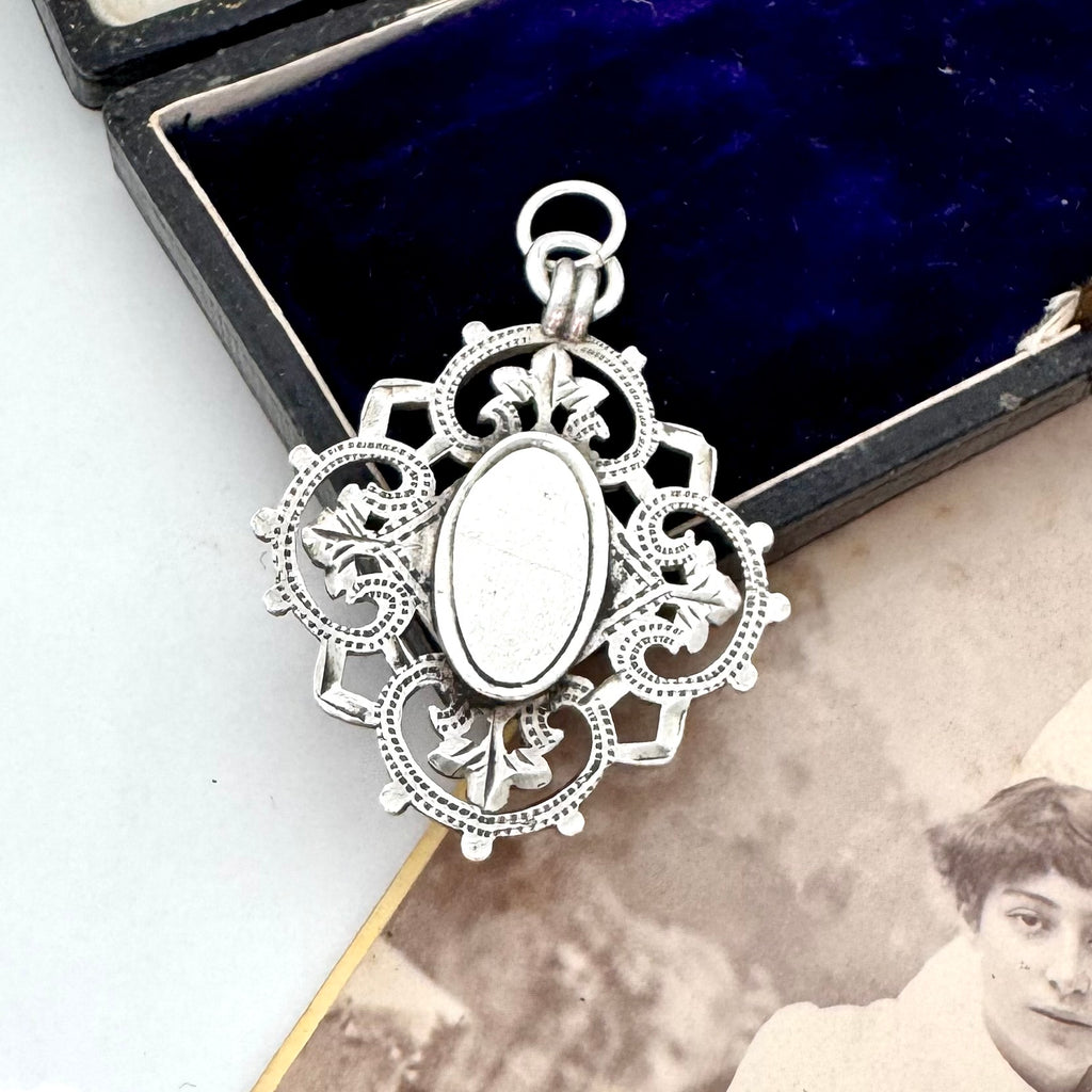 Decorative silver antique watch fob pendant on a vintage photograph
