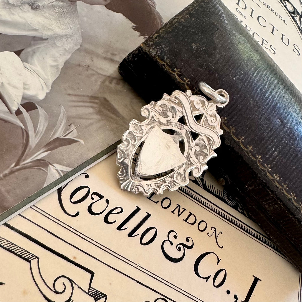 Antique silver watch fob pendant on an old document with 'Ovello & Co.' branding