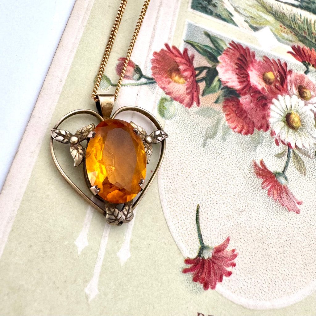 Antique heart-shaped pendant with a yellow gemstone on a floral card