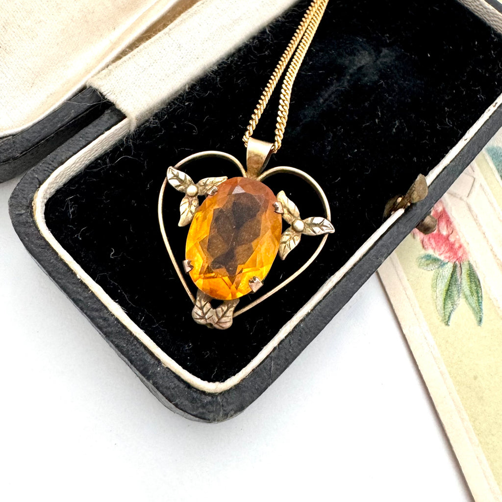 Antique heart-shaped pendant with a yellow gemstone in a black jewelry box