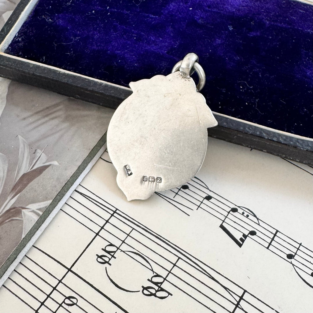 Antique silver and red enamel Lion Rampant watch fob pendant on a sheet of music