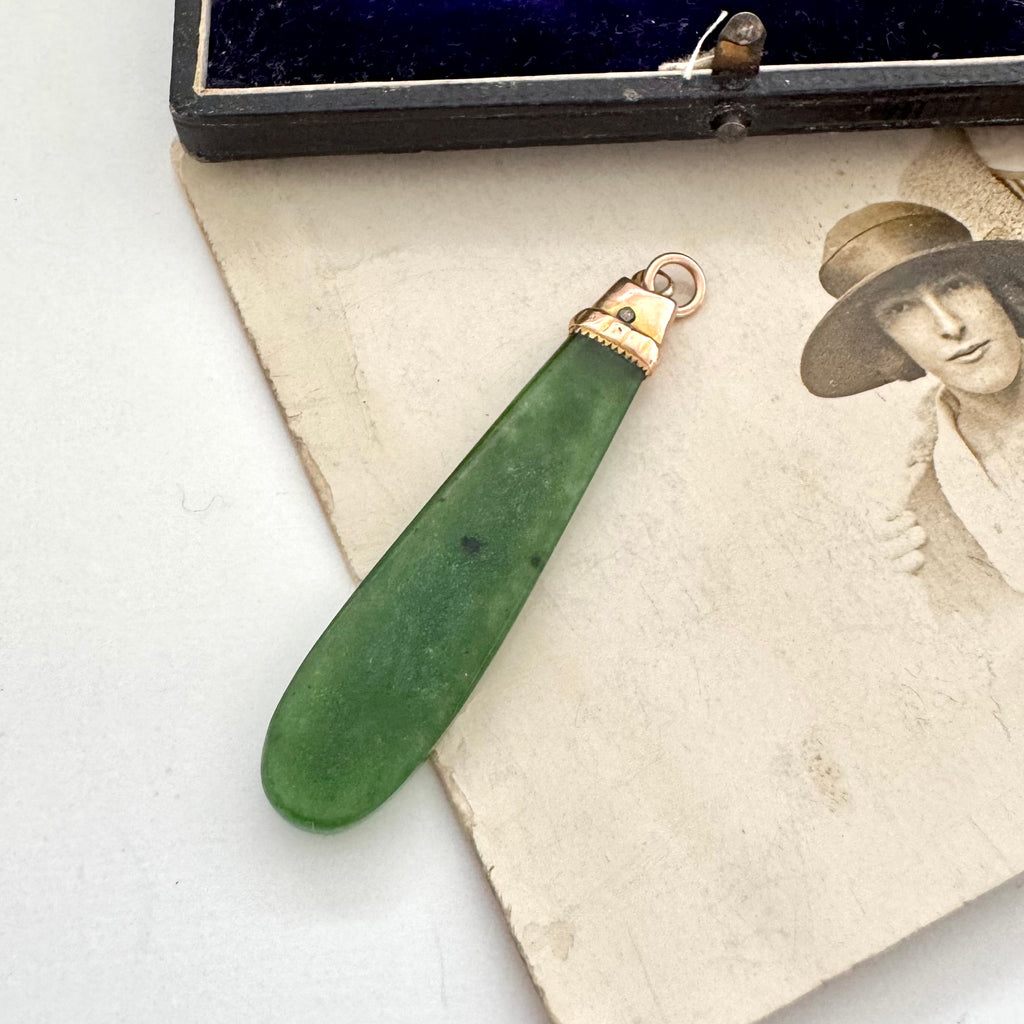 Antique 9ct rose gold and greenstone pendant on a vintage photograph