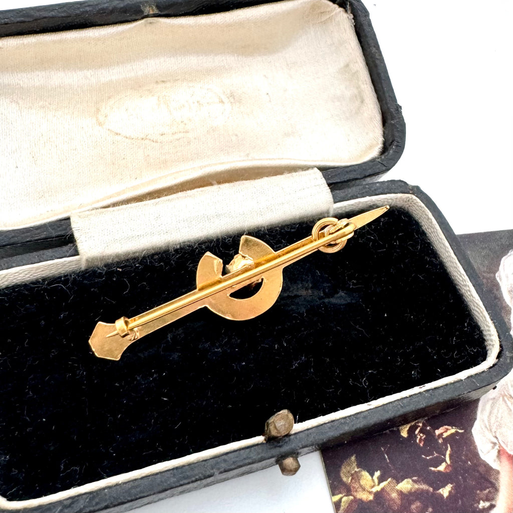 Gold tie clip in an open jewelry box with a white interior