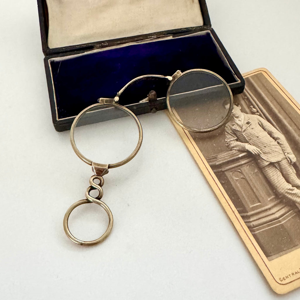 Vintage eyeglasses with a case and sepia-toned photo on a white background