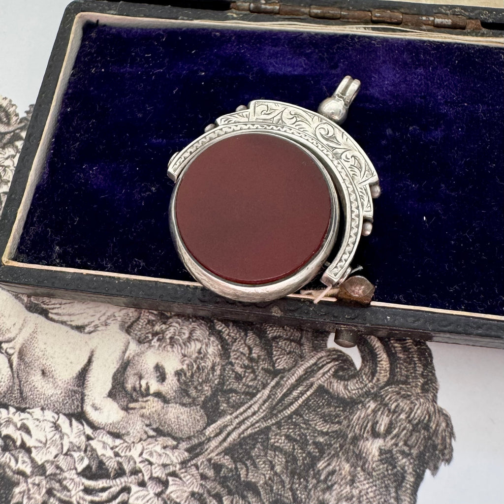 Antique 1896 Chester hallmarked carnelian and bloodstone spinning fob on a jewellery box.