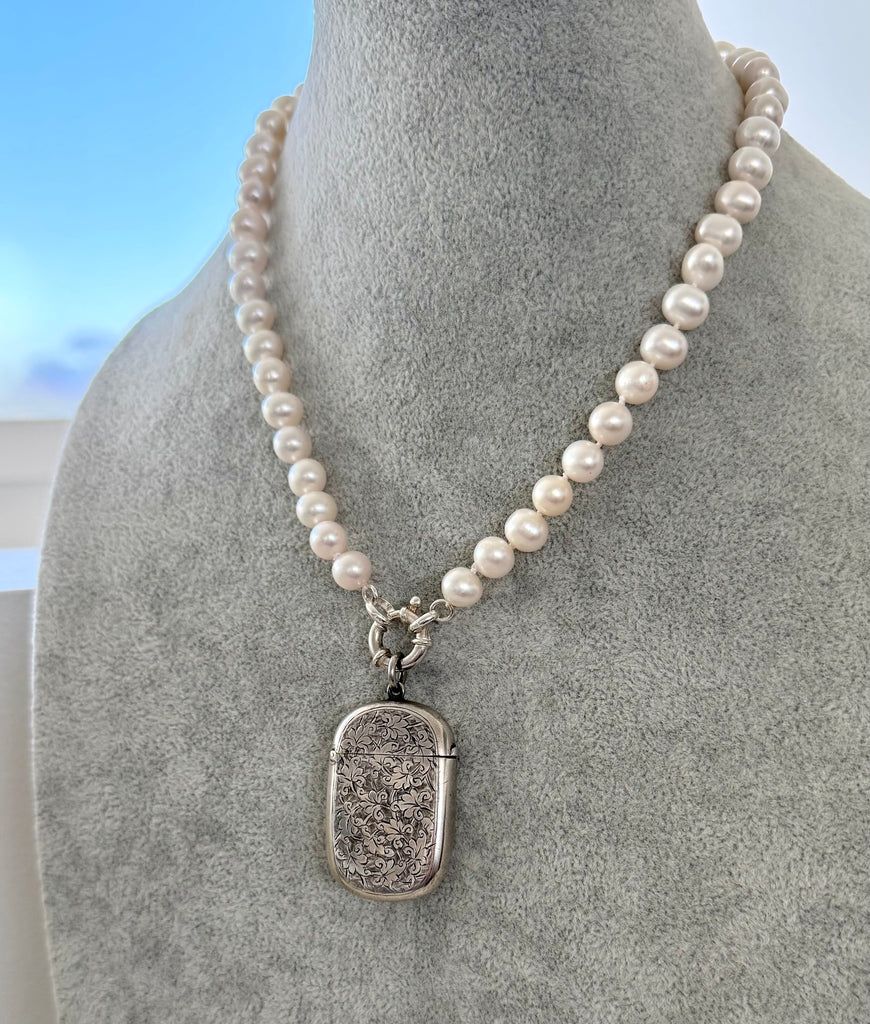 Pearl necklace with a sterling silver antique vesta case pendant on a mannequin bust.