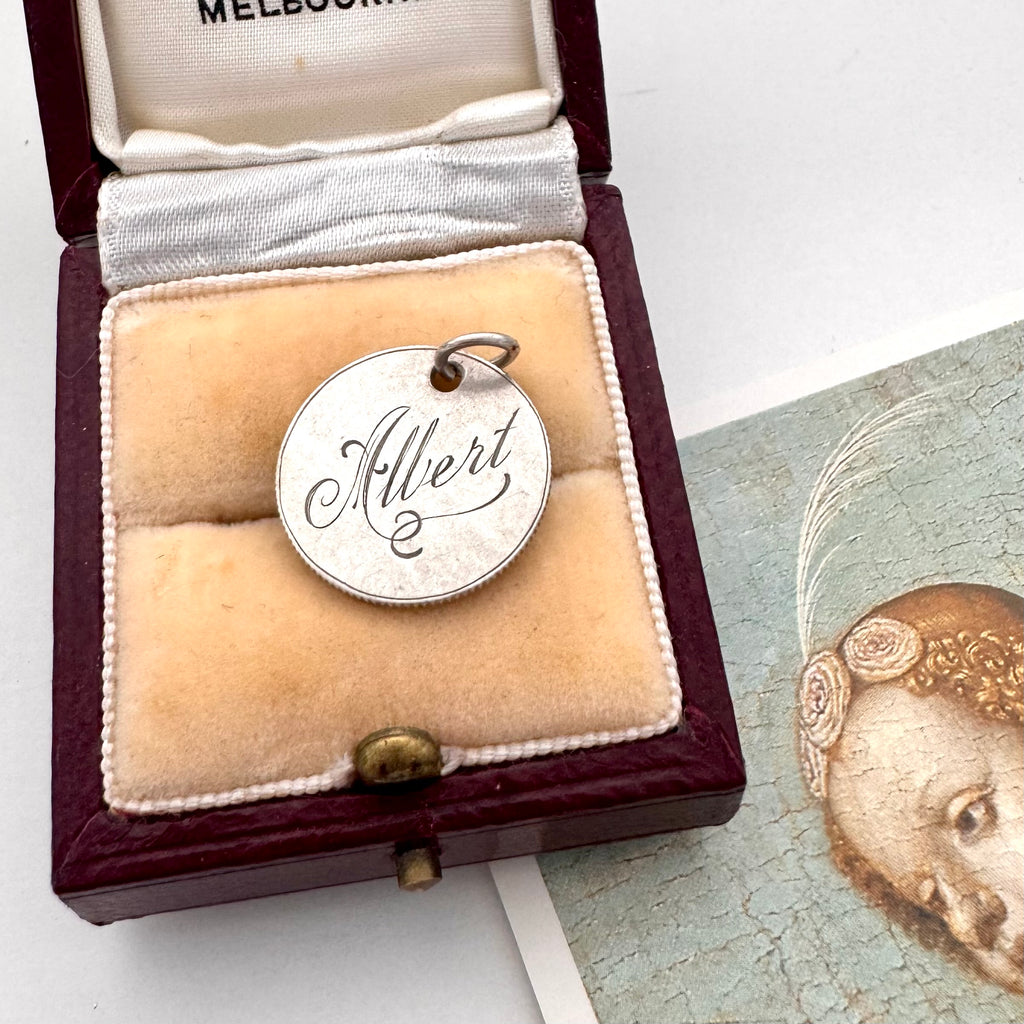 Antique silver British sixpence with 'Albert' engraved in a decorative box on an image of an angel.