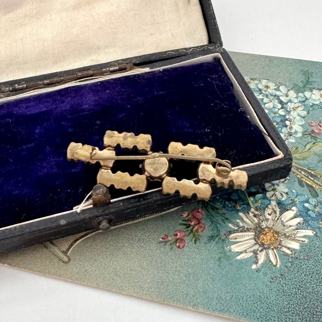 Back of Art Deco era blue paste brooch in an open jewellery box and a vintage postcard