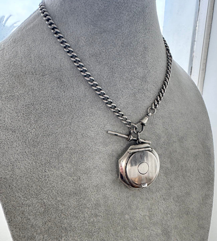 Silver necklace with a pendant on a mannequin bust.