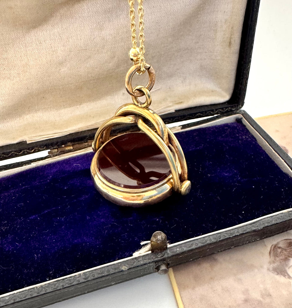 Rolled gold antique spinning fob with a dark stone on an old photograph and on an open jewellery box