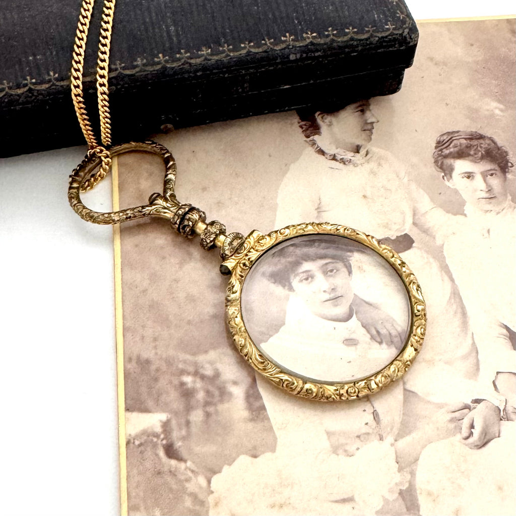 Antique gold magnifying glass necklace on an old photograph