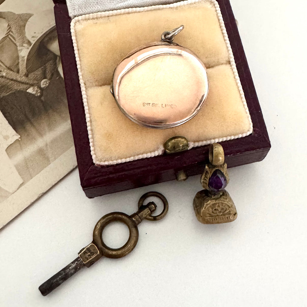 Vintage locket and key in a wooden box on a white surface
