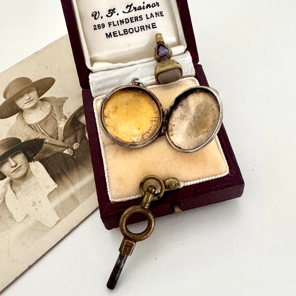 Antique watch key and open locket in a jewellery box with a photograph of women on the right