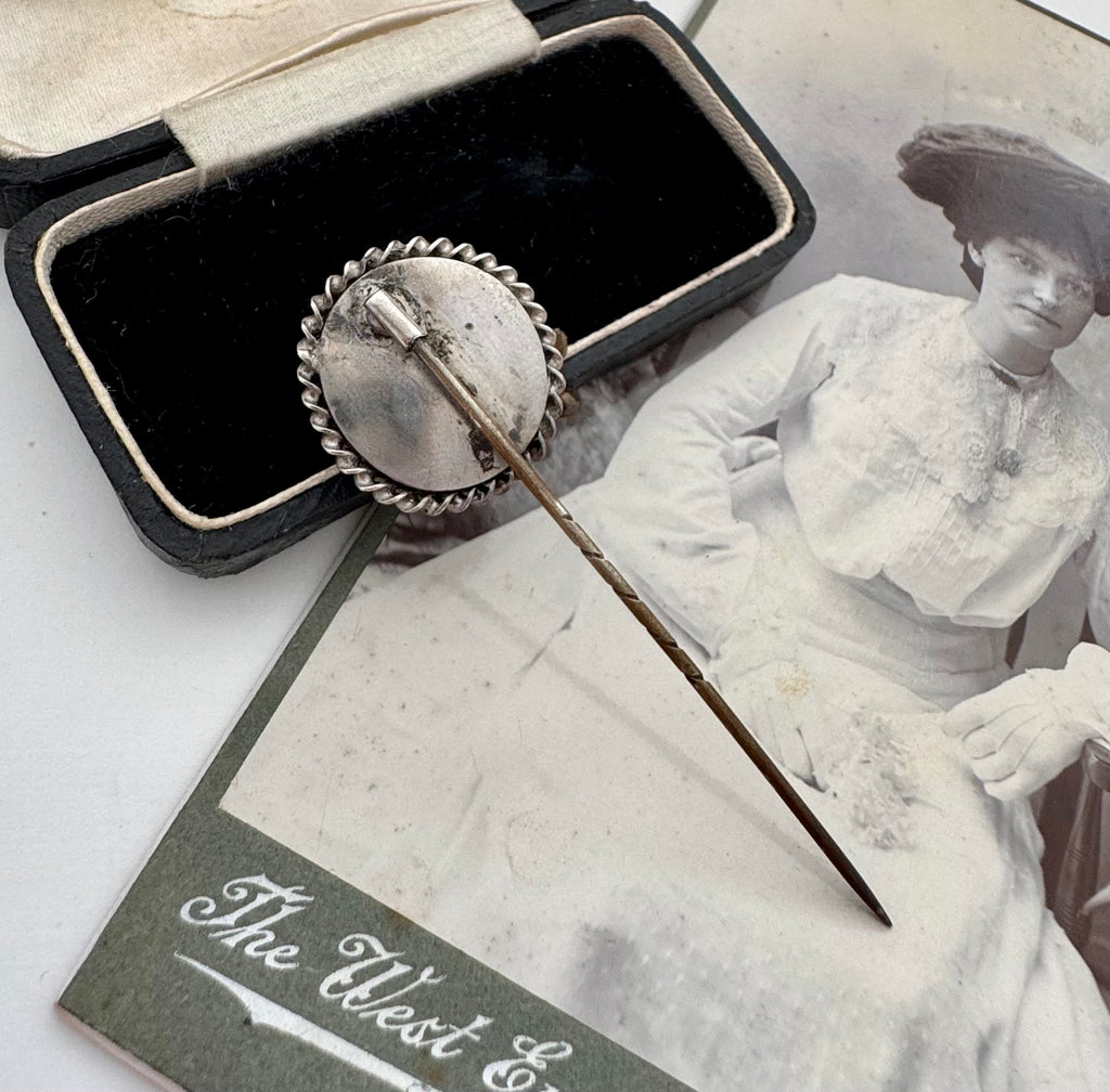Antique operculum shell pin on an old photograph of a woman in a white dress and hat.