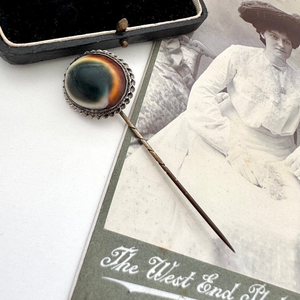 Antique operculum shell pin on an old photograph of a woman in a white dress and hat.
