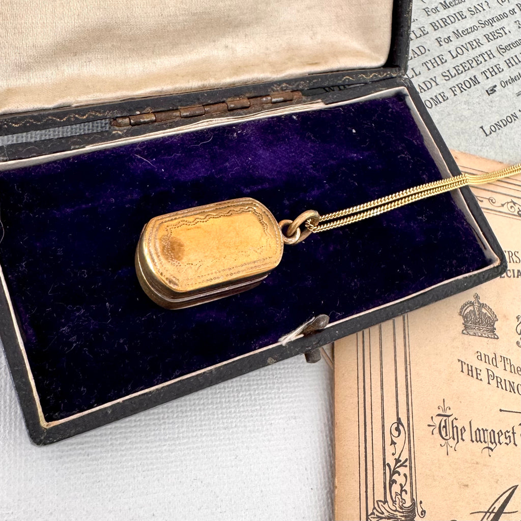 Antique pinchbeck vinaigrette on a chain with an old document in the background and on an old jewellery box