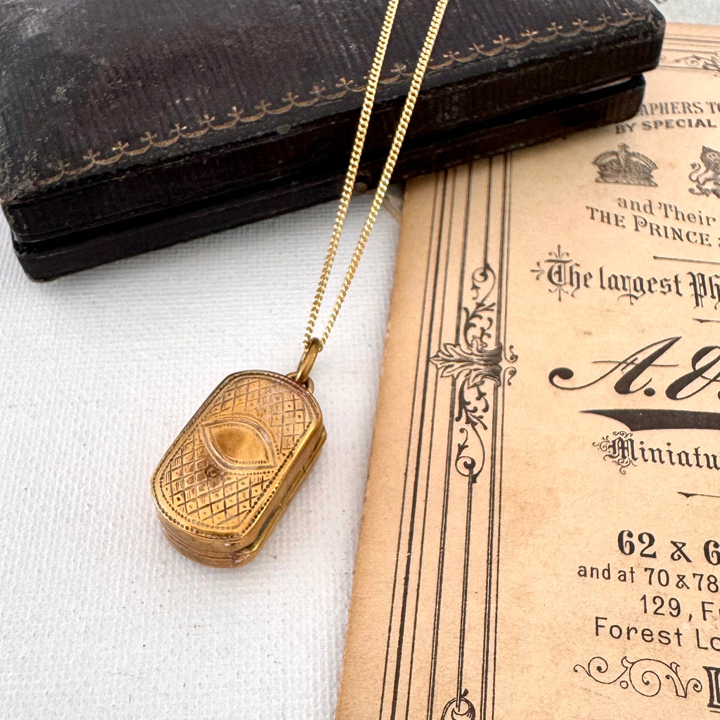 Antique pinchbeck vinaigrette on a chain with an old document in the background