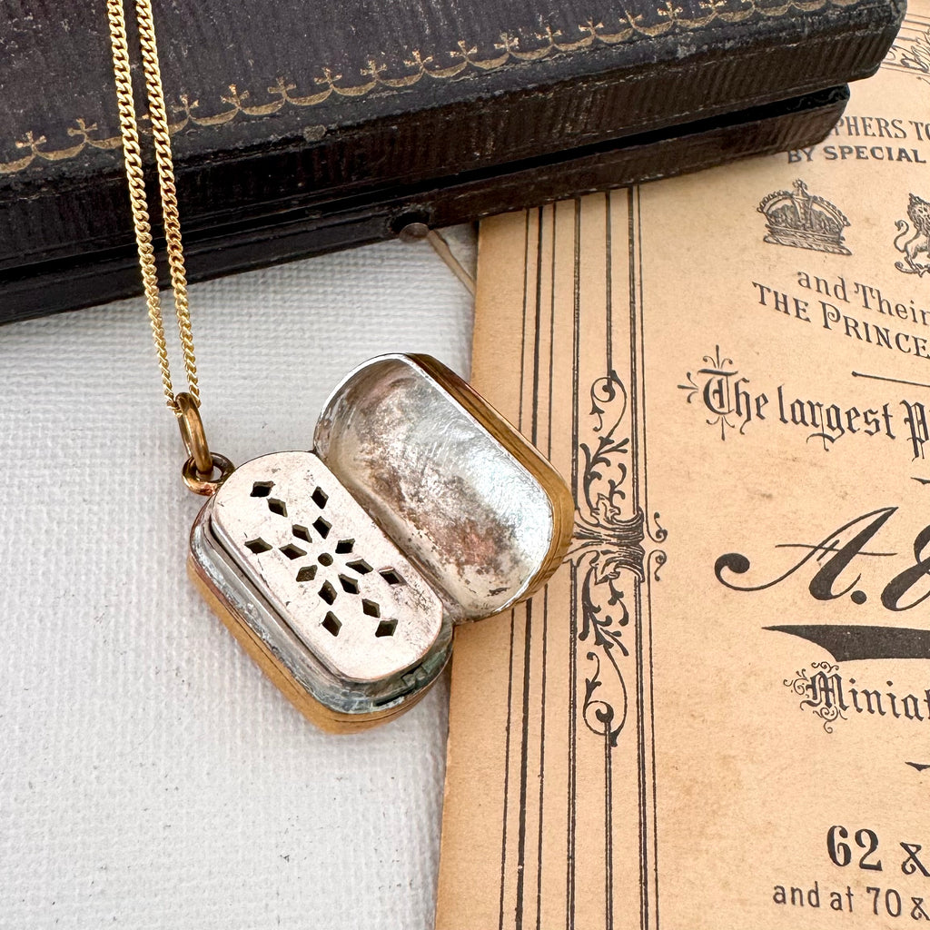 Open antique pinchbeck vinaigrette on a chain with an old document in the background