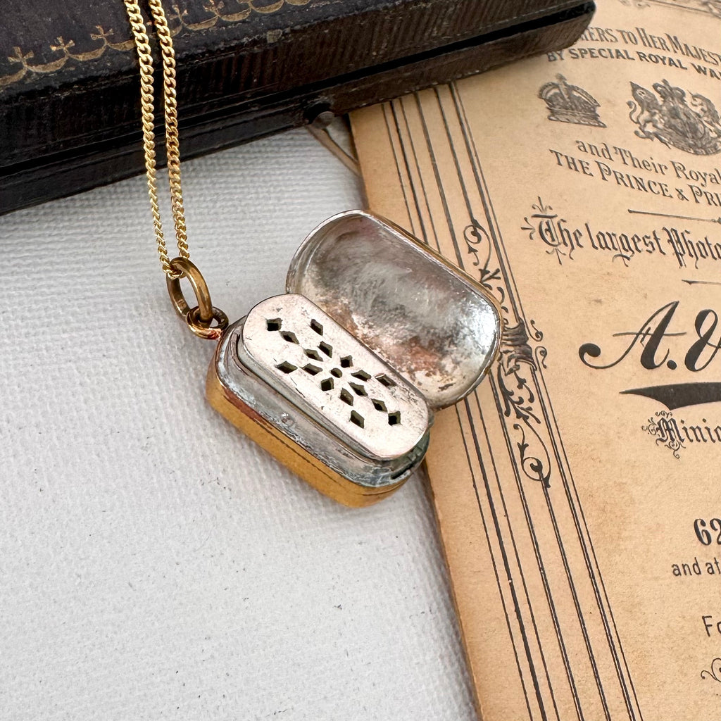 Open antique pinchbeck vinaigrette on a chain with an old document in the background
