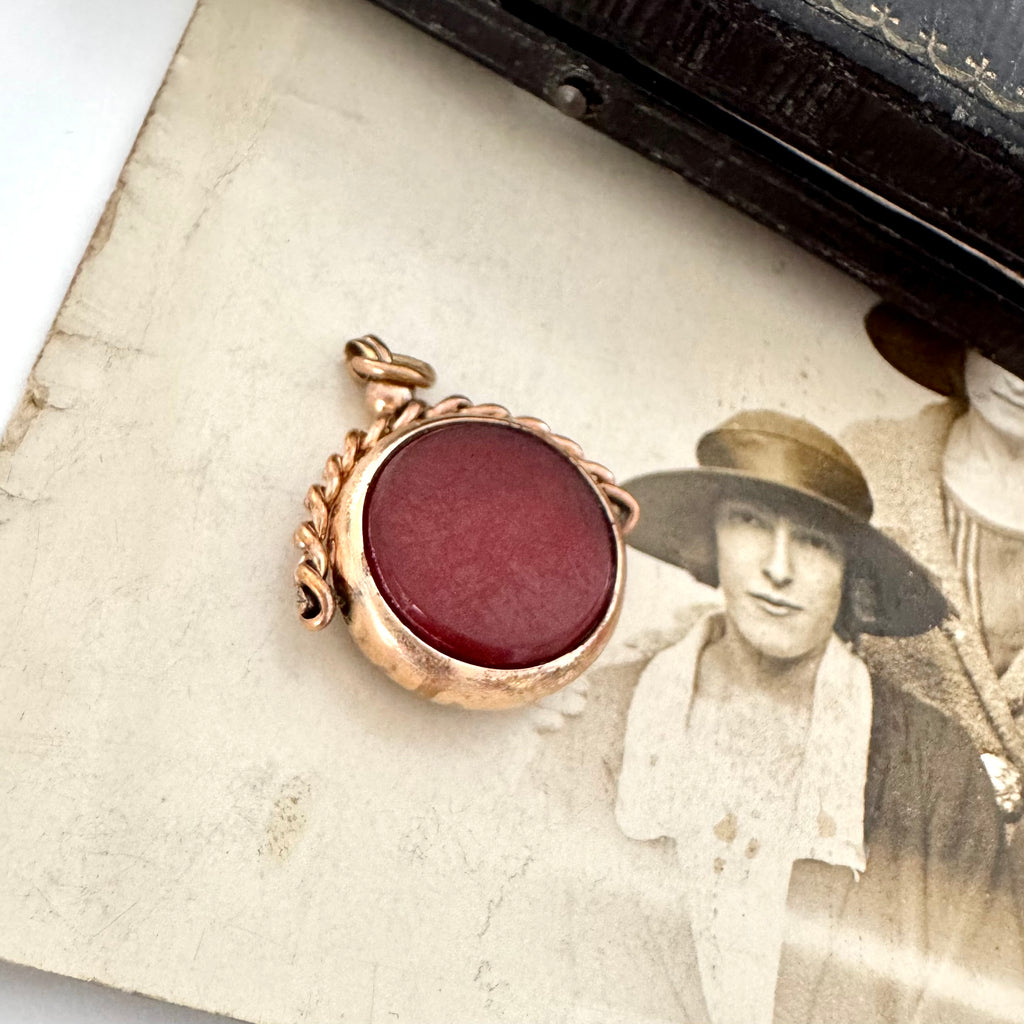 Antique rolled gold carnelian and bloodstone spinning fob on an antique photo of a woman and with a vintage jewellery box in the corner.