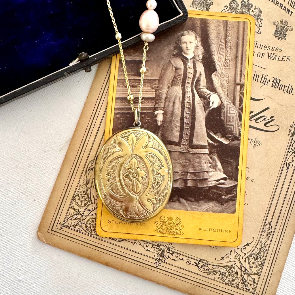 Antique locket on a gold and pearl chain on old photos and jewellery box