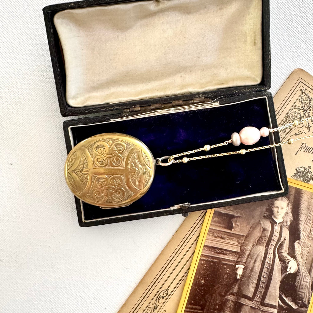 Antique locket on a gold and pearl chain on old photos and jewellery box