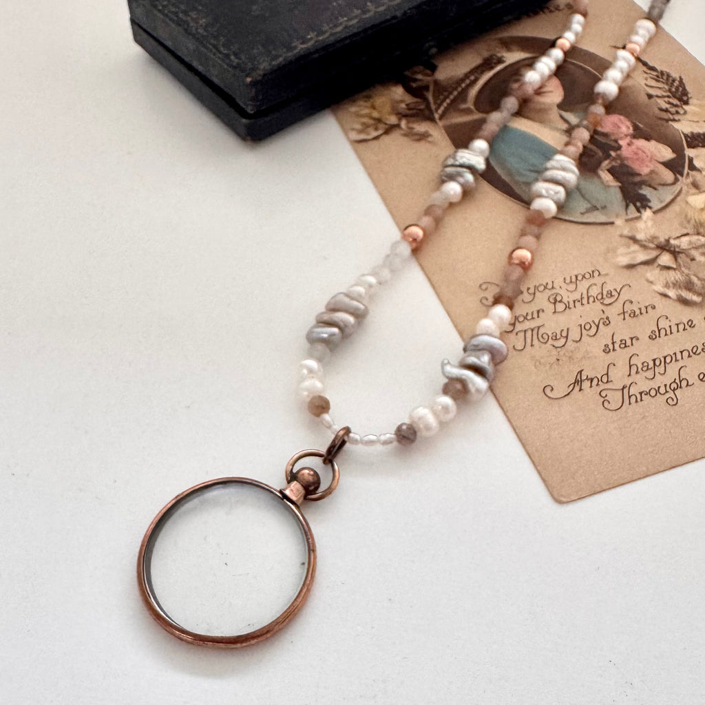 Antique rolled rose gold photo locket ith pearls and crystals on a vintage postcard and with an old jewellery box