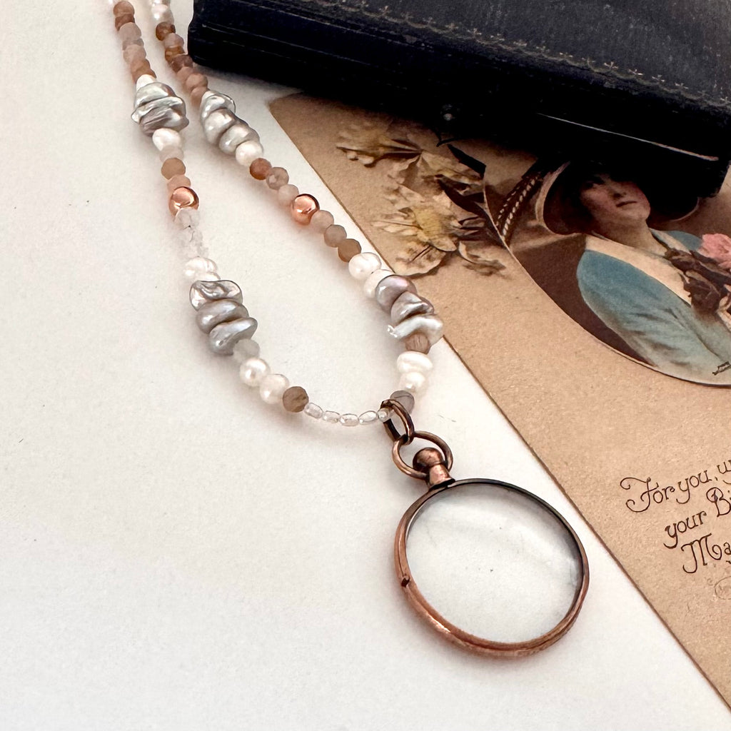 Antique rolled rose gold photo locket ith pearls and crystals on a vintage postcard and with an old jewellery box