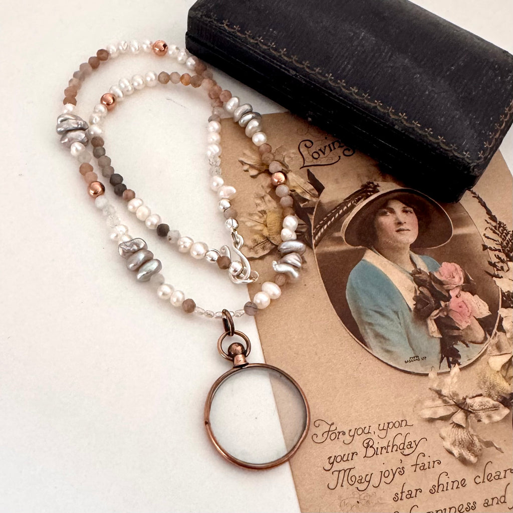Antique rolled rose gold photo locket ith pearls and crystals on a vintage postcard and with an old jewellery box