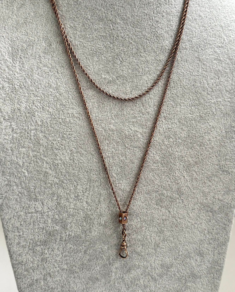 Antique A.H.B & C rolled rose gold guard chain with opal slider on a grey mannrquin