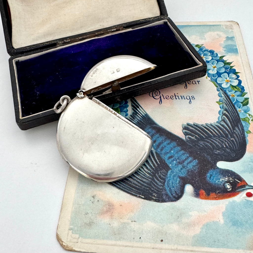 Antique silver round vesta case with a bird design on a vintage card