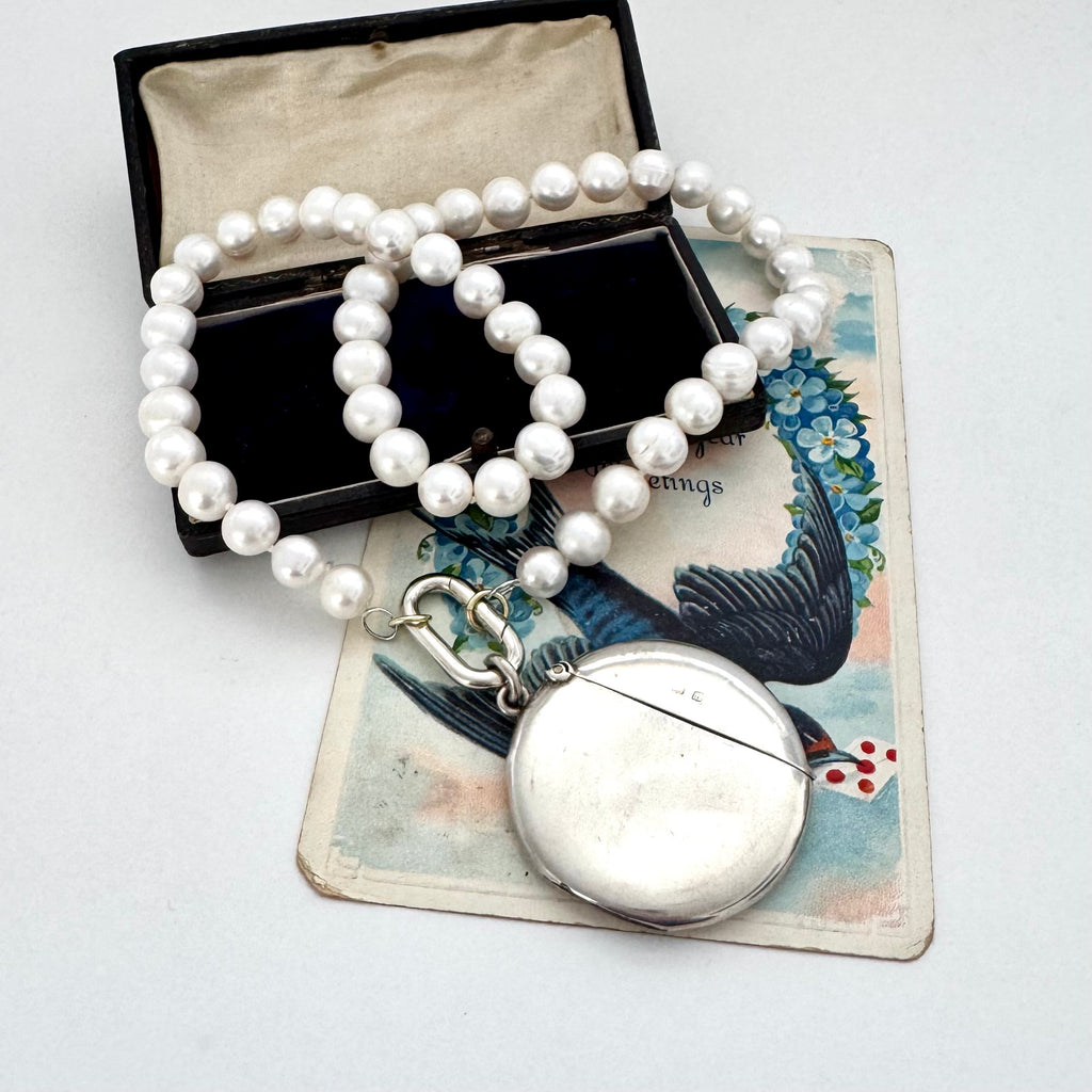 Pearl necklace with an antique silver vesta case on a decorative card