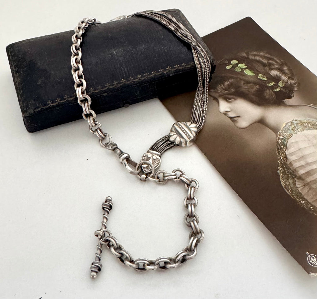 Antique albertina chain on a white background and with an old postcard and box