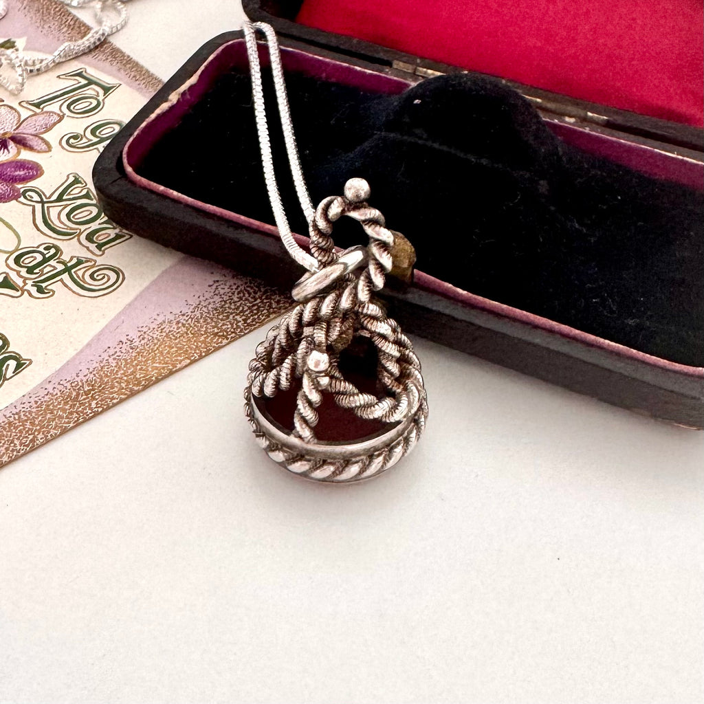 Antique silver and carnelian watch fob on a white background and with an old jewellery box